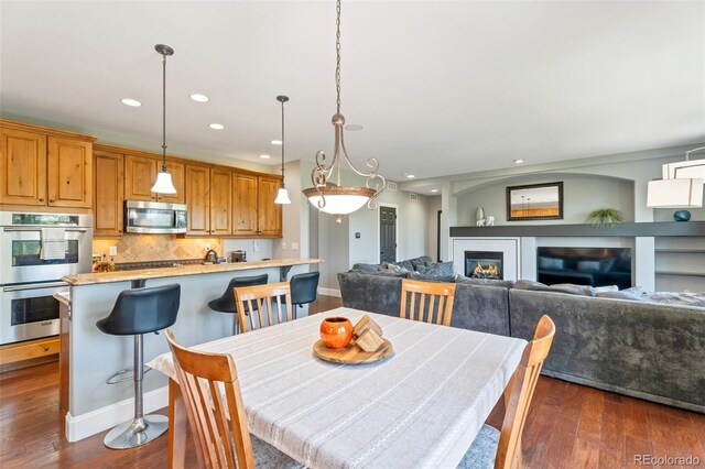 6988 S Riverwood Way, Aurora, CO 80016 - dining area featuring dark wood-style flooring, recessed lighting, baseboards, and a glass covered fireplace