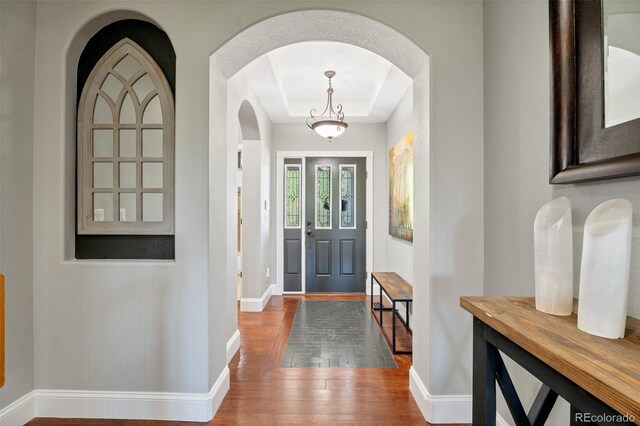 6988 S Riverwood Way, Aurora, CO 80016 - entrance foyer featuring hardwood / wood-style flooring, baseboards, arched walkways, and a tray ceiling