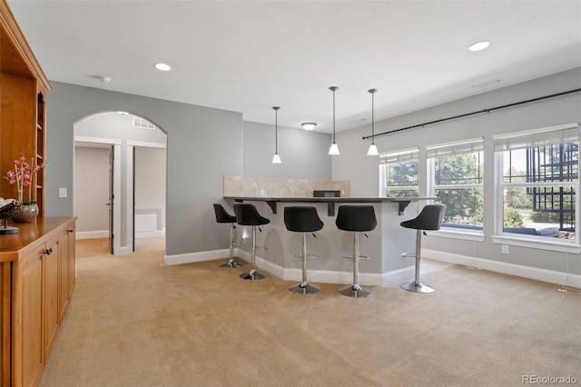 kitchen with a kitchen breakfast bar, light carpet, and decorative light fixtures