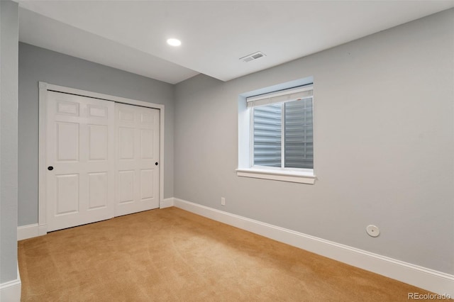 unfurnished bedroom with light colored carpet and a closet