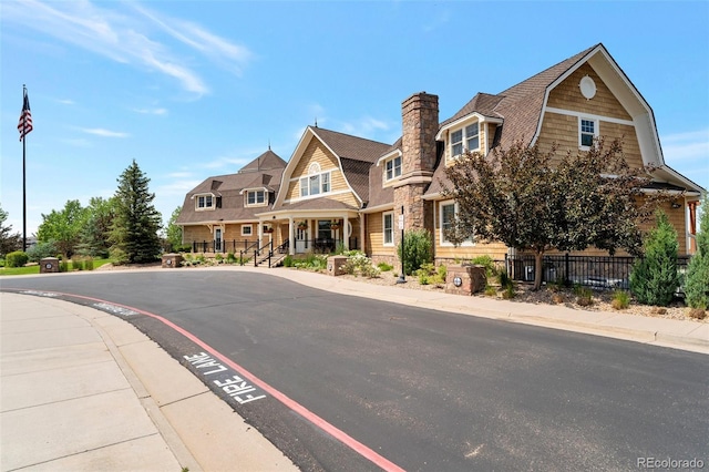 6988 S Riverwood Way, Aurora, CO 80016 - view of front of property featuring a gambrel roof, fence, stone siding, uncovered parking, and a chimney