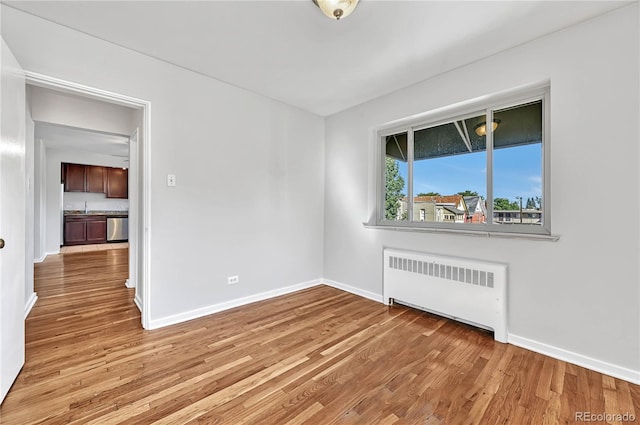 2100 N Franklin St Unit 15, Denver, CO 80205 - unfurnished room featuring radiator heating unit, baseboards, light wood-style floors, and a sink