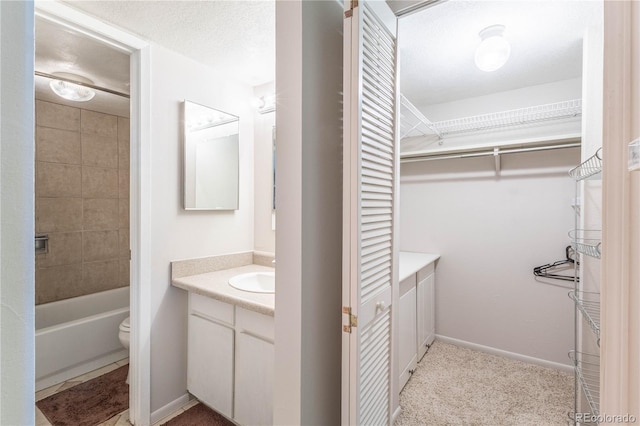 full bathroom featuring a textured ceiling, vanity, toilet, and tiled shower / bath