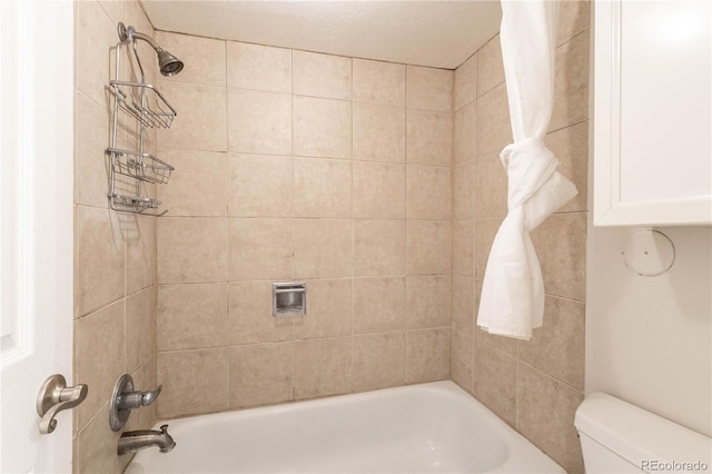 bathroom featuring toilet and tiled shower / bath