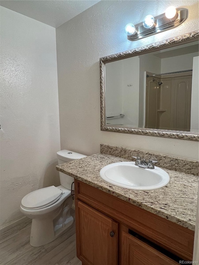 bathroom featuring toilet, vanity, wood-type flooring, and walk in shower