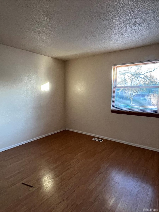 unfurnished room featuring dark hardwood / wood-style flooring and a textured ceiling