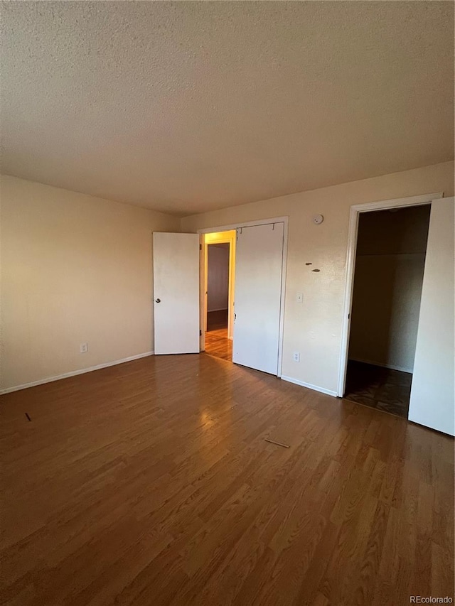 unfurnished bedroom with dark hardwood / wood-style flooring, a textured ceiling, and a closet