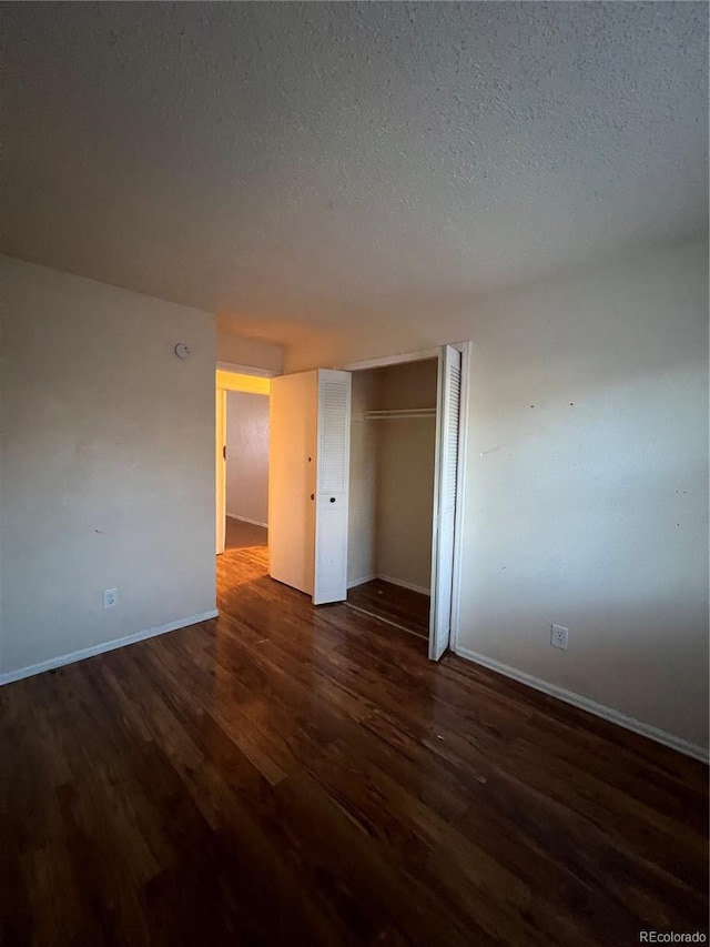 unfurnished bedroom with dark hardwood / wood-style flooring, a textured ceiling, and a closet