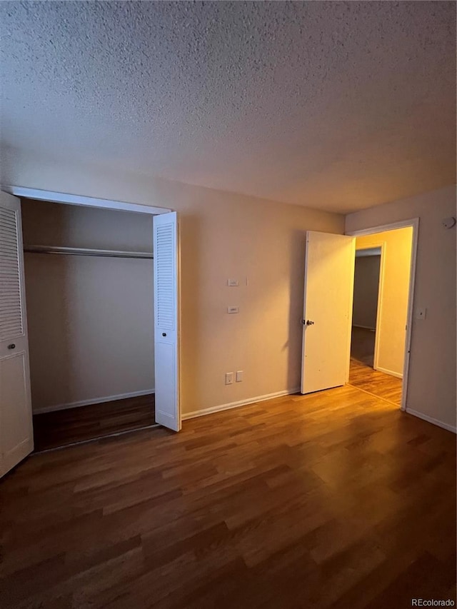 unfurnished bedroom with a closet, a textured ceiling, and hardwood / wood-style flooring