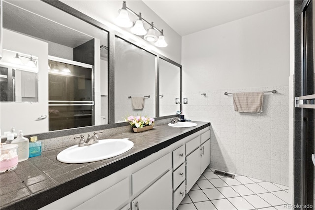 16673 E Kent Dr, Aurora, CO 80013 - full bathroom featuring double vanity, tile patterned flooring, tile walls, a shower with shower door, and wainscoting