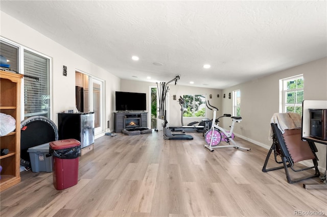 16673 E Kent Dr, Aurora, CO 80013 - workout area with light wood-style floors, recessed lighting, a glass covered fireplace, and a textured ceiling