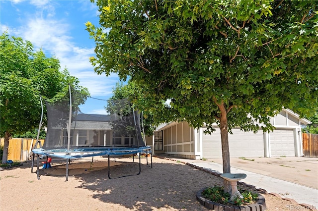 16673 E Kent Dr, Aurora, CO 80013 - view of yard featuring a trampoline, an outbuilding, a garage, and concrete driveway