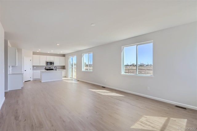 unfurnished living room with light hardwood / wood-style flooring and sink