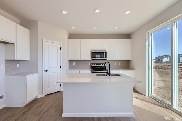 kitchen with white cabinets, appliances with stainless steel finishes, and an island with sink