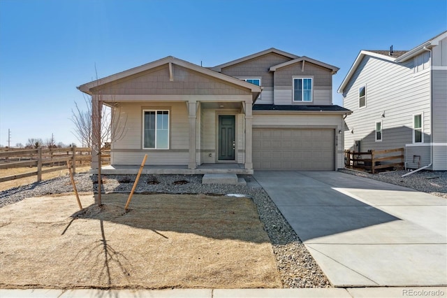 view of front of house with an attached garage, covered porch, fence, and concrete driveway