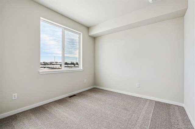 empty room featuring carpet, visible vents, and baseboards