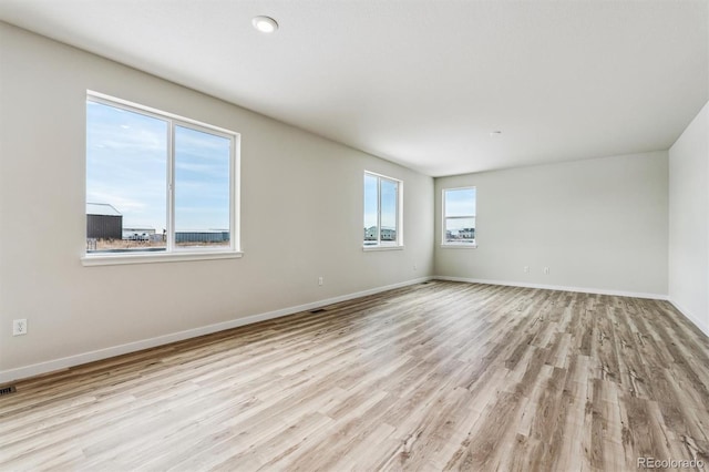 spare room featuring visible vents, light wood-style flooring, and baseboards