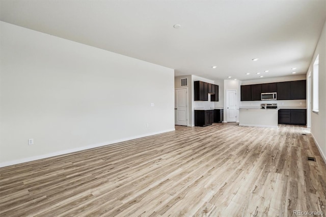 unfurnished living room with light wood-type flooring, visible vents, baseboards, and recessed lighting