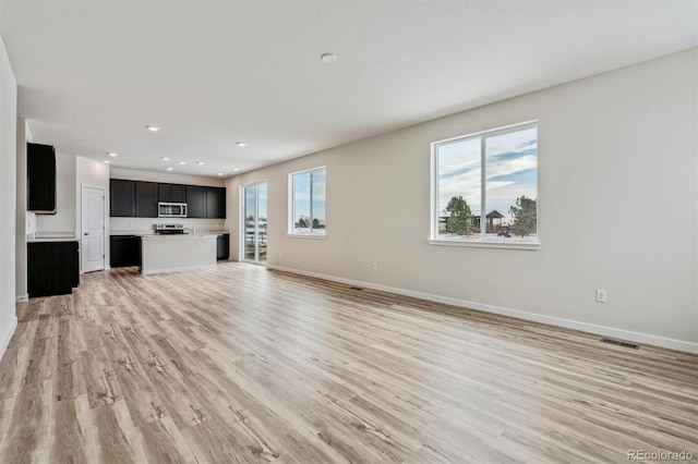 unfurnished living room with light wood-style flooring, visible vents, baseboards, and recessed lighting