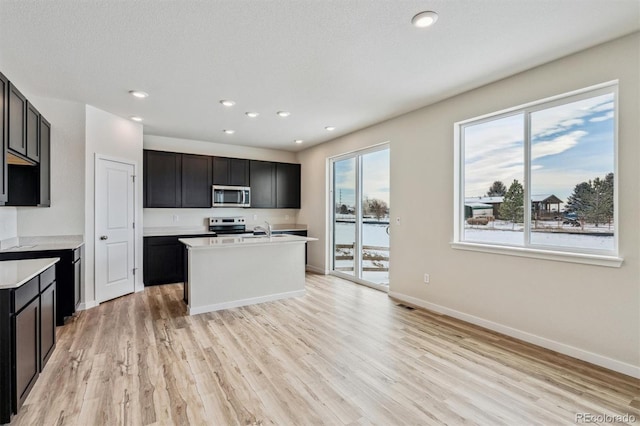 kitchen with stainless steel appliances, light wood-type flooring, light countertops, and baseboards