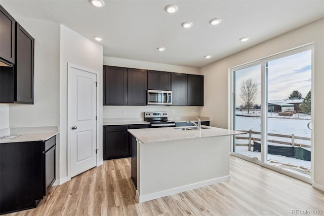 kitchen with stainless steel appliances, light wood finished floors, a sink, and light countertops