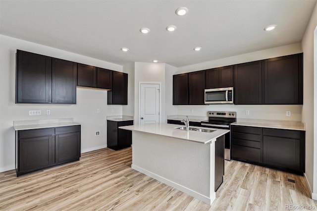 kitchen with light countertops, appliances with stainless steel finishes, light wood-type flooring, and a sink