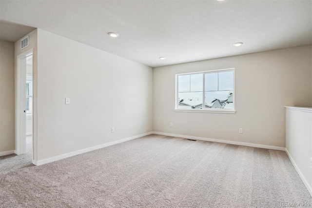 carpeted empty room featuring recessed lighting, visible vents, and baseboards