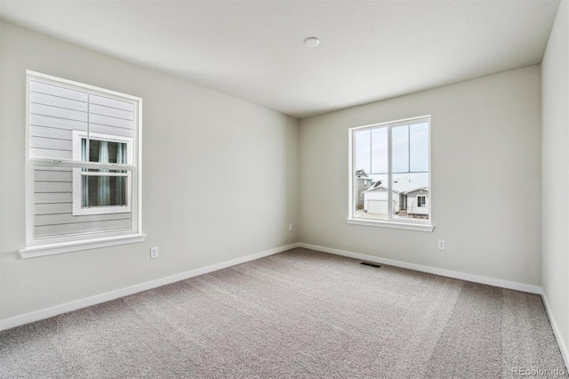 unfurnished room featuring baseboards, visible vents, and carpet flooring