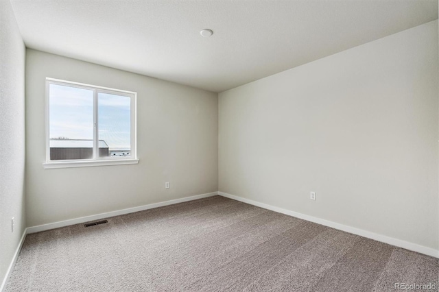 carpeted spare room with visible vents and baseboards