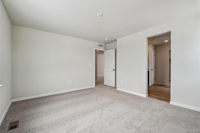 carpeted empty room with visible vents and baseboards