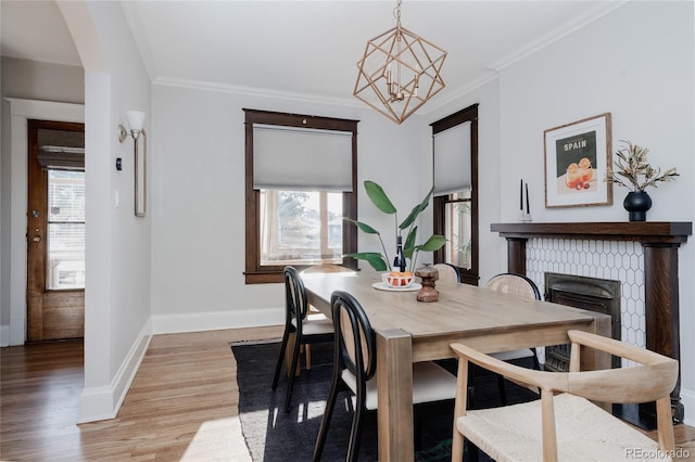 2096 S Logan St, Denver, CO 80210 - dining space featuring plenty of natural light, light wood-type flooring, a chandelier, a fireplace, and crown molding