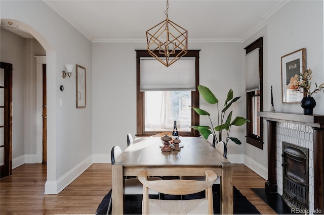 2096 S Logan St, Denver, CO 80210 - dining room with arched walkways, wood finished floors, a chandelier, crown molding, and a fireplace with flush hearth