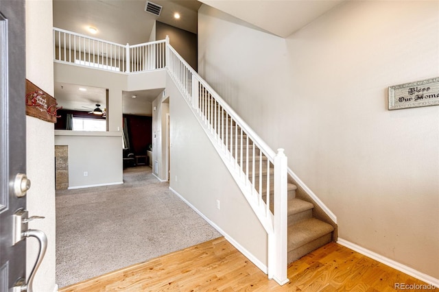 stairs featuring ceiling fan, hardwood / wood-style floors, and a high ceiling