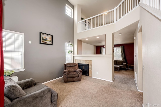 carpeted living room with a towering ceiling and a tiled fireplace