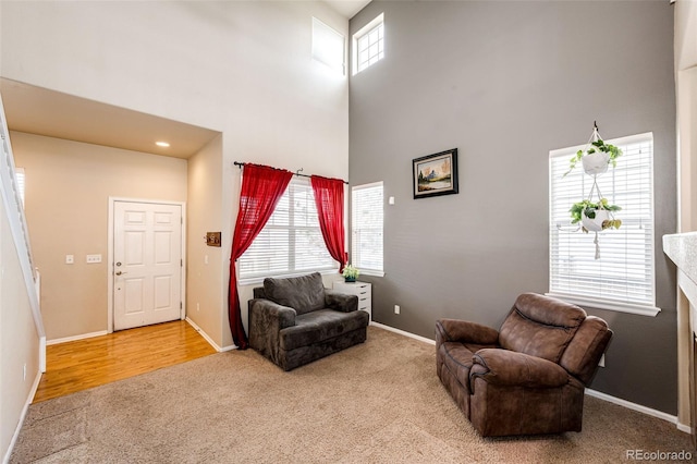 sitting room featuring carpet flooring, a healthy amount of sunlight, and a high ceiling