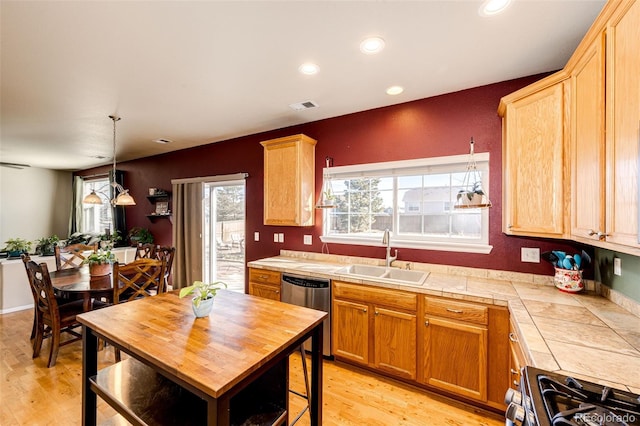 kitchen featuring appliances with stainless steel finishes, light hardwood / wood-style flooring, tile counters, and sink