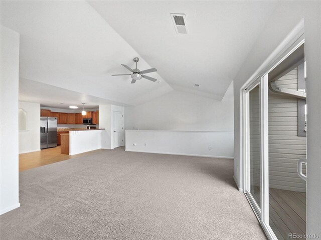 unfurnished living room featuring ceiling fan, light colored carpet, baseboards, vaulted ceiling, and visible vents