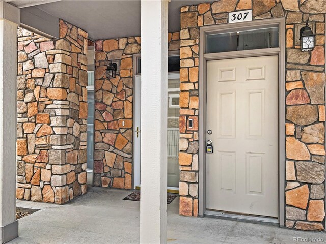 property entrance with a porch and stone siding