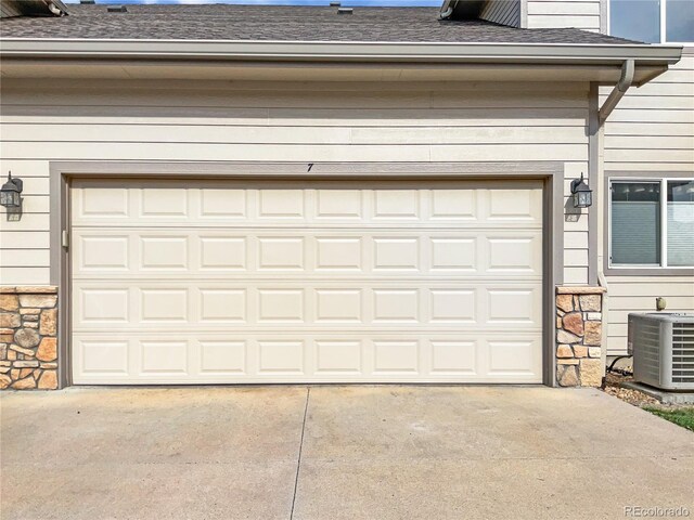 garage with central air condition unit and concrete driveway
