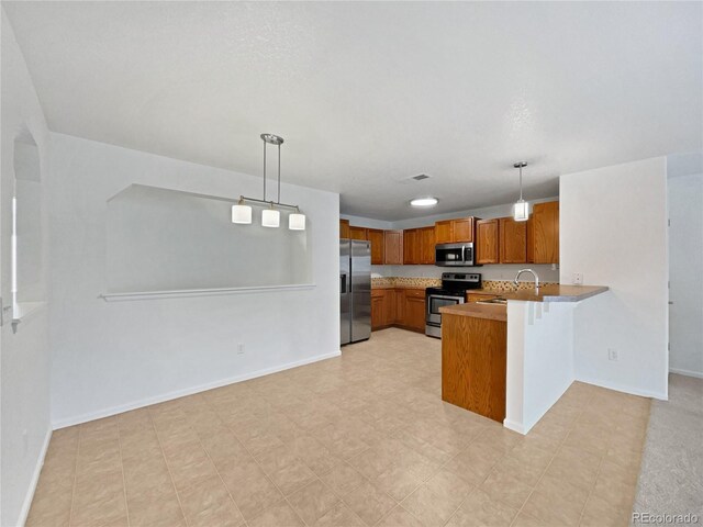 kitchen with visible vents, a peninsula, brown cabinets, appliances with stainless steel finishes, and hanging light fixtures