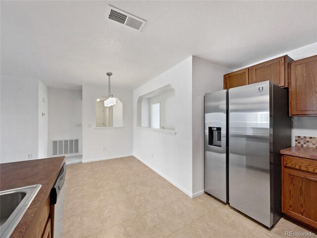 kitchen featuring visible vents, a sink, dishwasher, and stainless steel fridge with ice dispenser