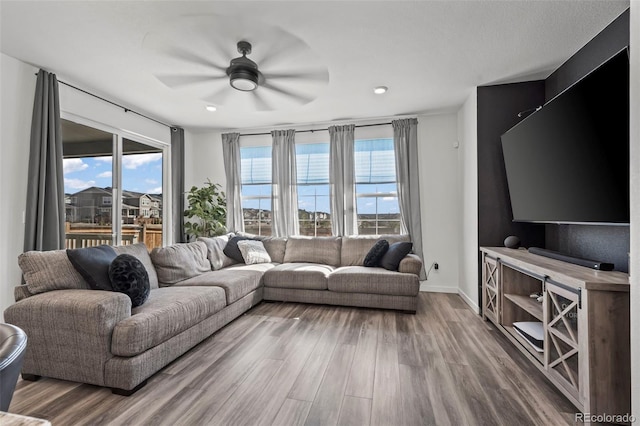 living area with ceiling fan, baseboards, plenty of natural light, and wood finished floors