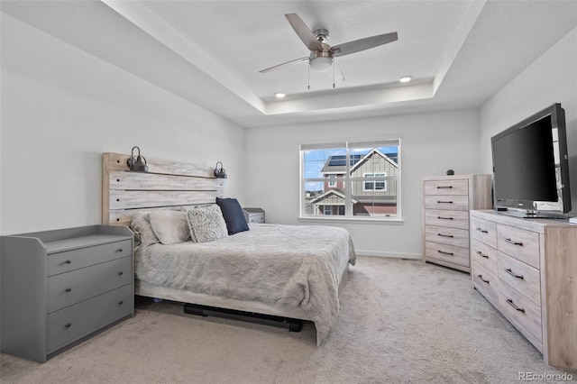 bedroom featuring a tray ceiling, a ceiling fan, baseboards, and light carpet