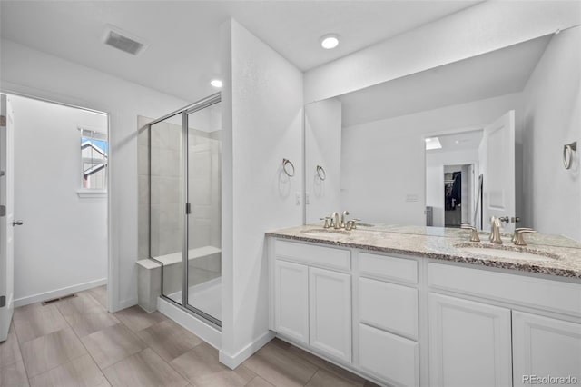 bathroom with a shower stall, double vanity, visible vents, and a sink