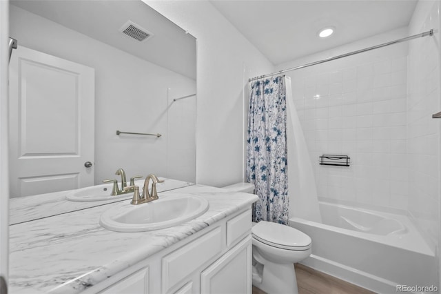 full bathroom with vanity, wood finished floors, visible vents, shower / tub combo, and toilet