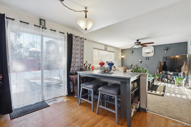 kitchen with kitchen peninsula, a textured ceiling, light hardwood / wood-style floors, and ceiling fan