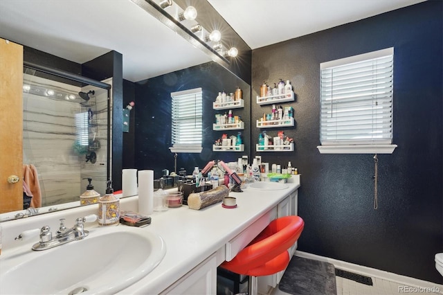 bathroom featuring a shower with door and vanity