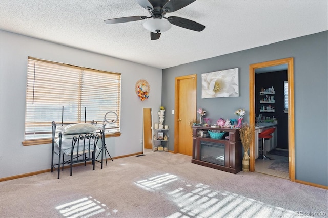 interior space with a textured ceiling, light colored carpet, and ceiling fan