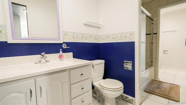 full bathroom with combined bath / shower with glass door, toilet, tile patterned floors, and vanity