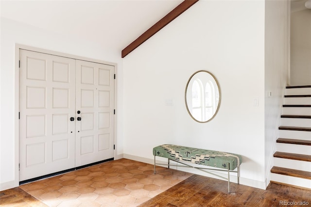 entrance foyer featuring vaulted ceiling with beams, baseboards, and stairway